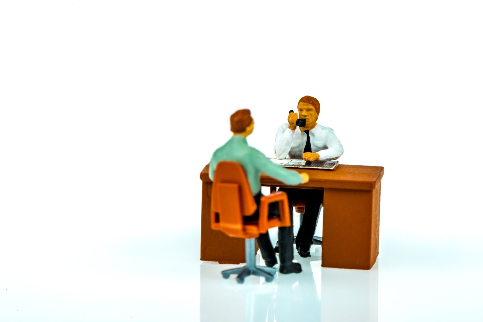 Twee miniatuurfiguren in gesprek aan een bureau