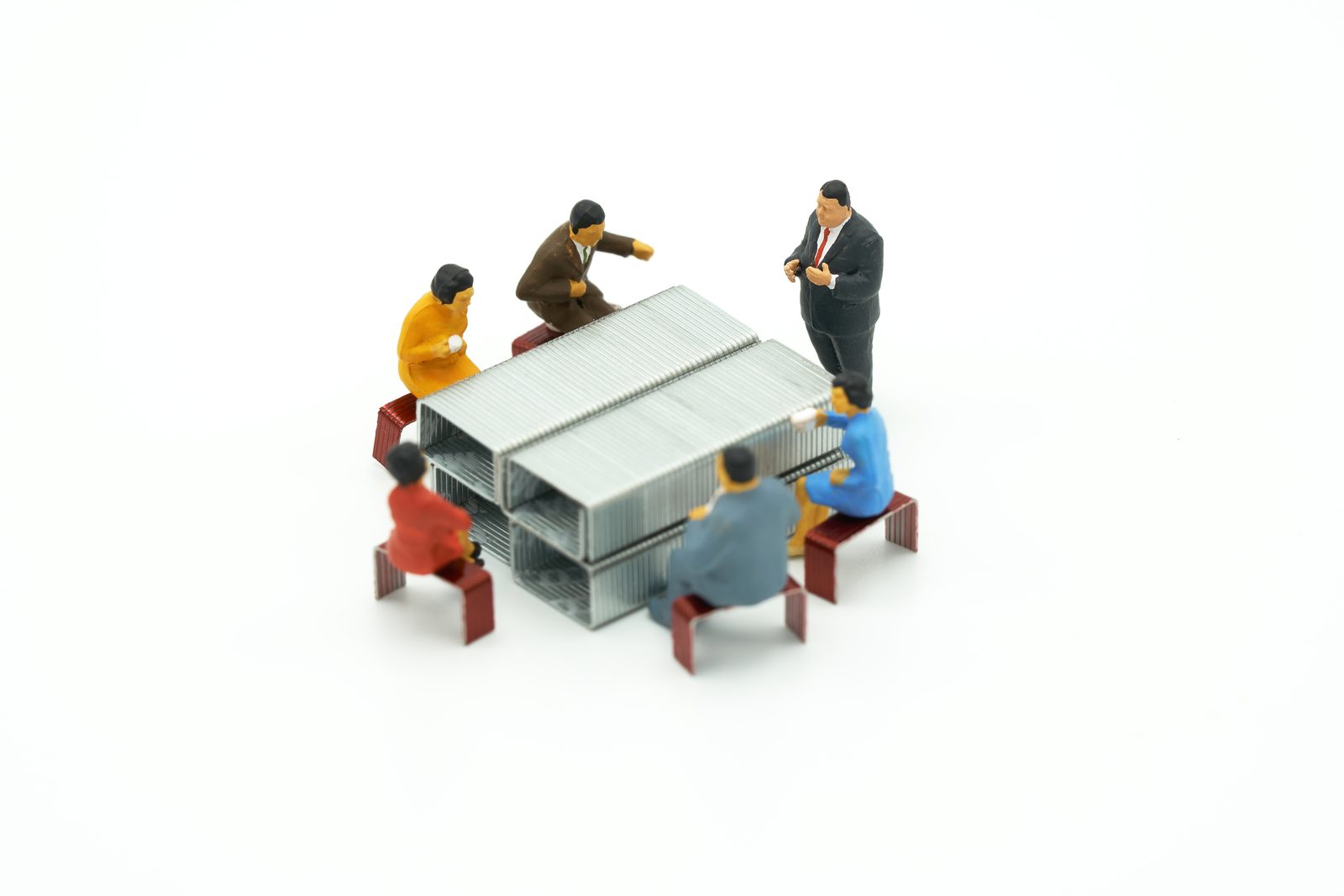 Miniatuurfiguren vergaderen rond een tafel