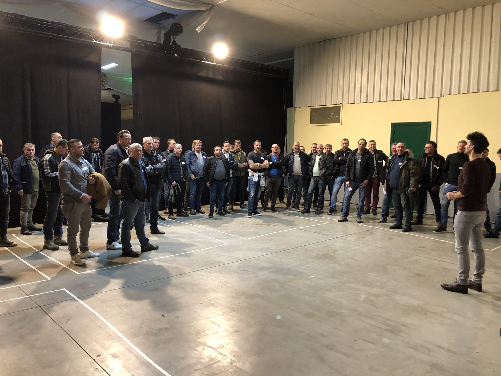 Grote groep deelnemers verzameld in een zaal tijdens een oefening